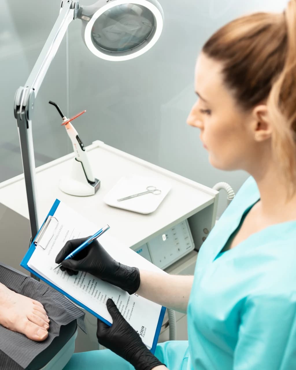 Specjalistka Strefy Podologii zapisuje wywiad z pacjentem podczas konsultacji podologicznej